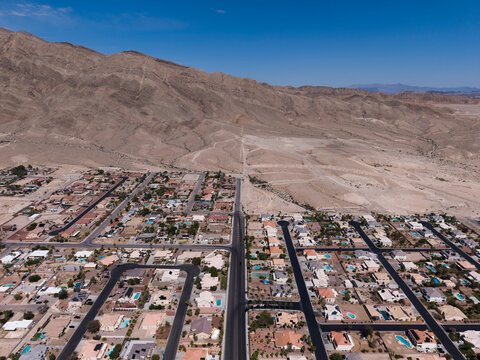 Wide drone perspective of a residential community next to a massive barren mountain range