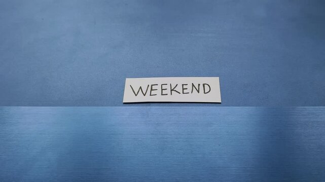 Weekend word written on white paper placed on top of personal laptop computer keyboard. Happy week end getaway leisure trip planning reminder. Employee waiting or anticipation for holiday concept.