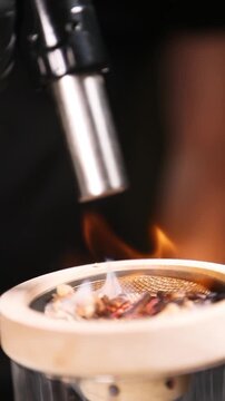 Barman encendiendo un ahumador de vidrio con soplete para un c&oacute;ctel. Barman profesional encendiendo un ahumador de virutas de madera con soplete. C&oacute;ctel ahumado, t&eacute;cnica de bar vanguardista.