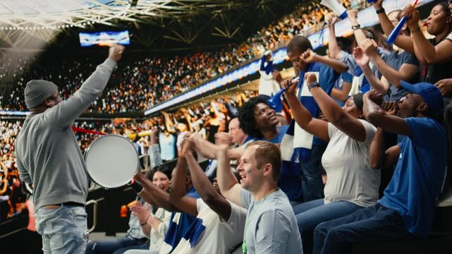 Fan leader with megaphone and drum energizing soccer supporters in stadium stands, family cheering and enjoying fun times with their son at stadium, football match celebration, parenthood.