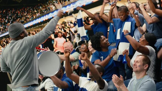 Fan leader with megaphone and drum energizing soccer supporters in stadium stands, family cheering and enjoying fun times with their son at stadium, football match celebration, parenthood.