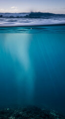 Split shot of a breaking ocean wave above and a sunlit underwater scene with rocky bottom, symbolizing adventure and the duality of nature.
