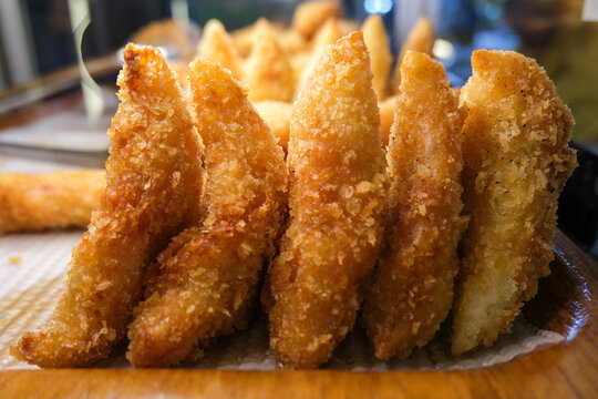 Triangular, breaded, and deep-fried risoles arranged on a wooden tray, showing their golden-brown, crispy exterior showcasing appetizing textures and appealing to lovers of crispy, savory snacks