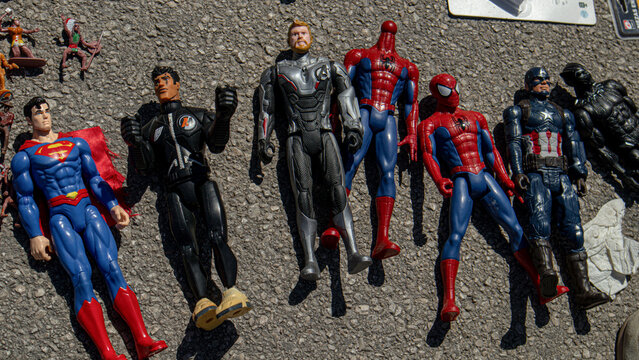 Polop, SPAIN - May 10, 2026.Collection of second hand superhero action figures on asphalt including Superman and Spider Man laid out for sale or display