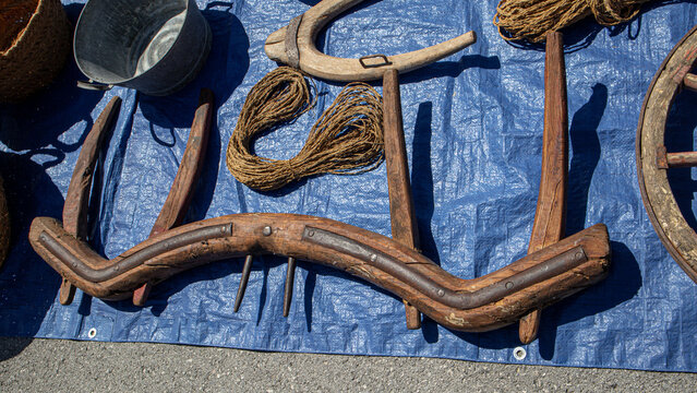 Display of vintage wooden ox yokes and coils of rope at flea market on blue tarp