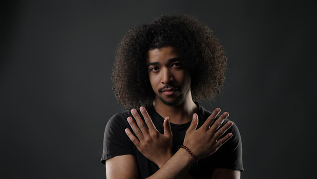Young man with afro looking at camera, hands crossed, expressing stop or refusal