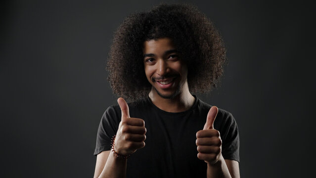 Young man with afro hair giving two thumbs up, expressing approval