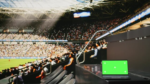 Green screen on laptop inside modern football stadium with green field, tribunes and soccer pitch for live match in the world tournament, match day in a sports venue with audience.