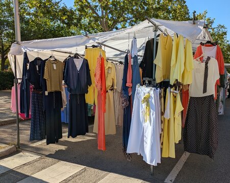 Colorida ropa de moda retro de verano, colgada en un puesto de un mercadillo de ropa vintage de segunda mano, instalado en una calle de Madrid, Espa&ntilde;a