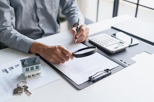 Asian businessman holding magnifying glass and checking documents