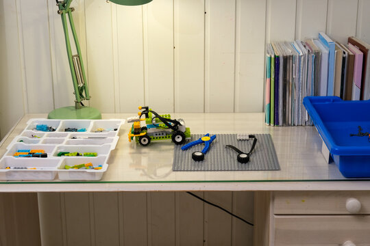 Interactive robotics kit laid out on table, open notebook, tablet, scattered bricks. Kids engineering project scene. Children assembling robotic set on desk. STEM education. Programming electric toys