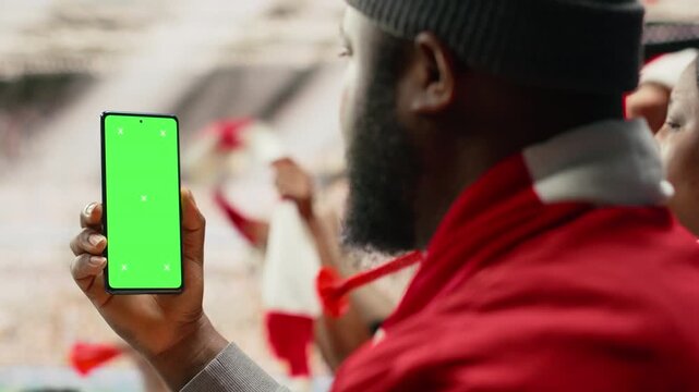 Smartphone mockup screen on phone held by soccer fan in the stadium stands during world championship football match, energetic cheering crowd at authentic sports event full of pride.