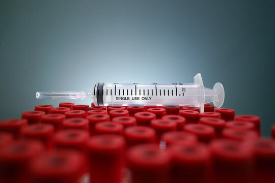 Medical Syringe on Laboratory Rack, A plastic medical syringe rests horizontally across a collection of red-capped tubes in a science lab