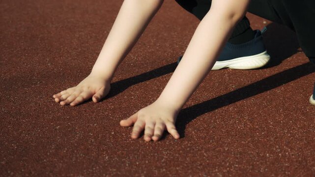 Children's pens touch the safe rubber crumb coating on the playground, in kindergarten, at school or at the stadium and show the class. Close-up.