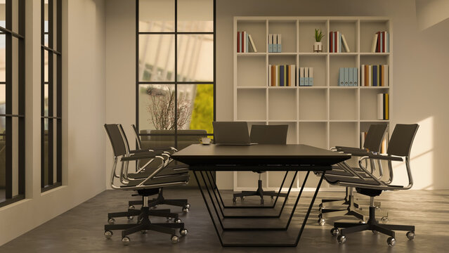Black table and swivel chairs beside white bookshelf and glass wall of meeting room in modern office