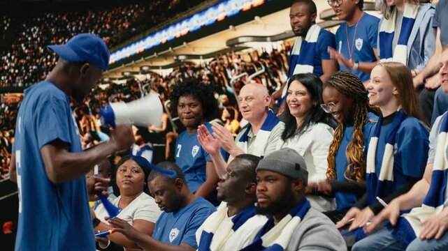 Excited football fan leader using bullhorn to unite blue supporter group in stadium stands during live soccer match atmosphere, passionate football fans in the supporter section singing chants.
