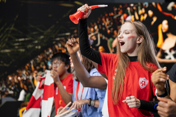 Teenager football fan cheering for the winning team from stadium stands, girl with face paint jumping and screaming after national team wins the world championship. Raised fists and joy. © DC Studio