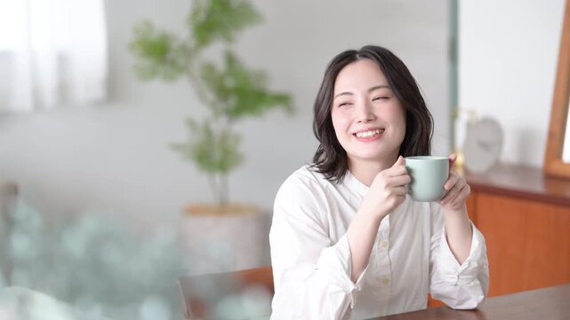 朝のくつろぐ時間にマグカップを持つ笑顔の女性ライフスタイル上半身の動画