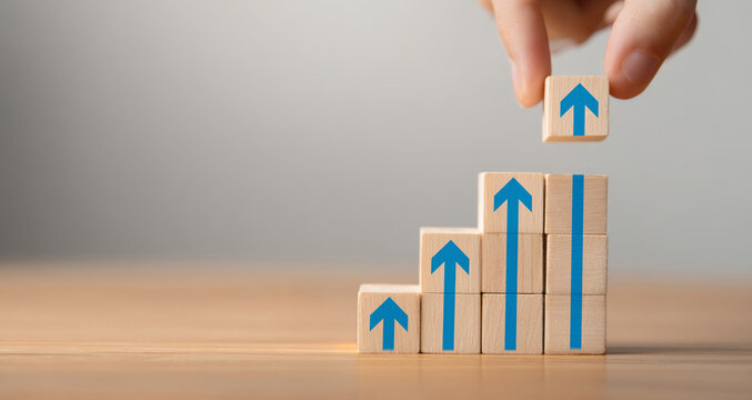 Business growth success depicted through a ladder career path concept. Wooden blocks stacked as step stairs with an upward arrow. Increase in productivity, sales, and income. career advancement