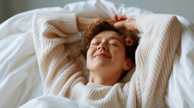 Young woman with freckles enjoying a peaceful morning in bed with cozy sweater