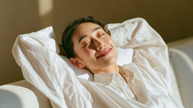 Young woman relaxing peacefully with eyes closed in soft sunlight on a couch