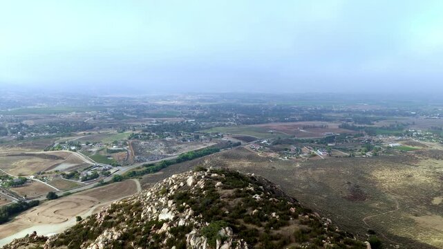 Expansive farmlands and rolling hills under a cloudy sky in Temescal Valley. Ideal for use in projects related to rural landscapes or weather patterns.