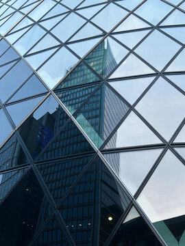 Moderne Glasfassade eines Wolkenkratzers mit geometrischem Rautenmuster und Spiegelungen von B&uuml;rogeb&auml;uden in der Londoner City