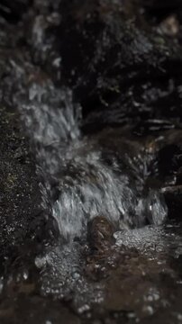 Cinematic close up of flowing water in dark natural stream