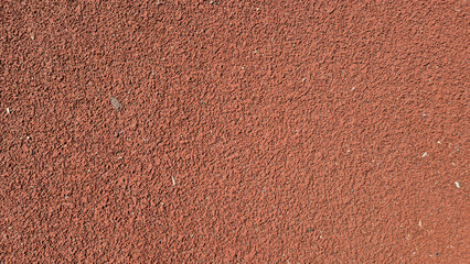 Fototapeta premium ​A close-up shot of a textured, reddish-brown synthetic running track surface.