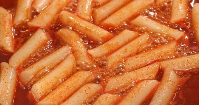 Process of cooking the Korean national dish tteokbokki. The tteokbokki in sauce are fried in a pan.