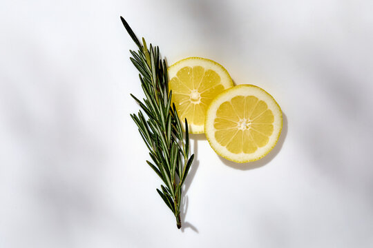 Rosemary and sliced lemon on white background