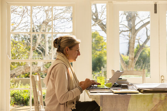 profile of adult woman typing on her laptop in her home office
