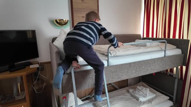 Little boy climbing up ladder to bunk bed