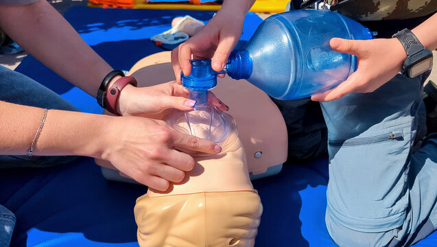 Children learning first aid during cpr training on a medical mannequin. Kids practicing artificial ventilation using an ambu bag resuscitator.