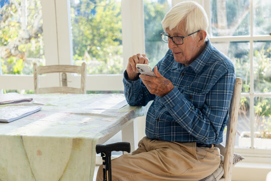 elderly man sitting at table using smart phone