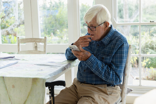 elderly man sitting at table using smart phone
