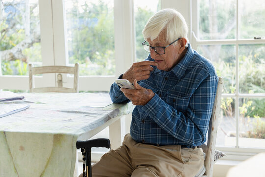 elderly man sitting at table using smart phone