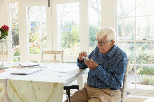 elderly man sitting at table using smart phone