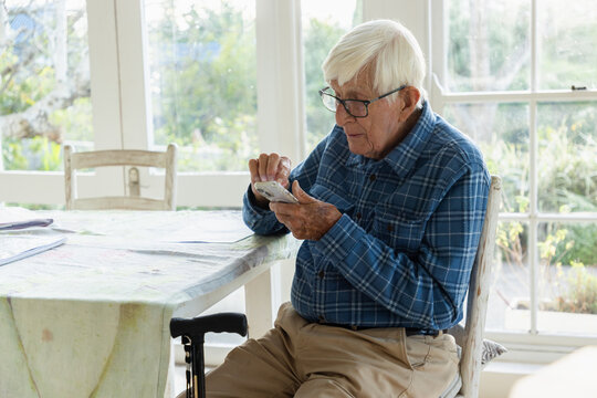 elderly man sitting at table using smart phone