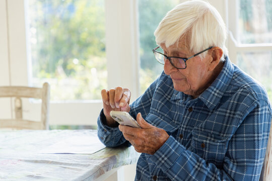 elderly man sitting at table using smart phone