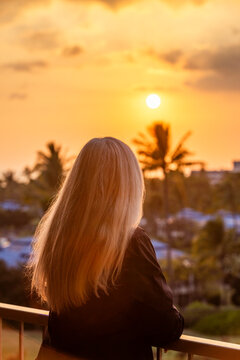Rear view of blonde woman viewing sunset from deck