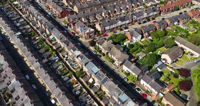 Aerial drone footage of rows of terraced housing and suburban streets in the city of York North Yorkshire England showing brick homes gardens roads and residential urban development in the summer