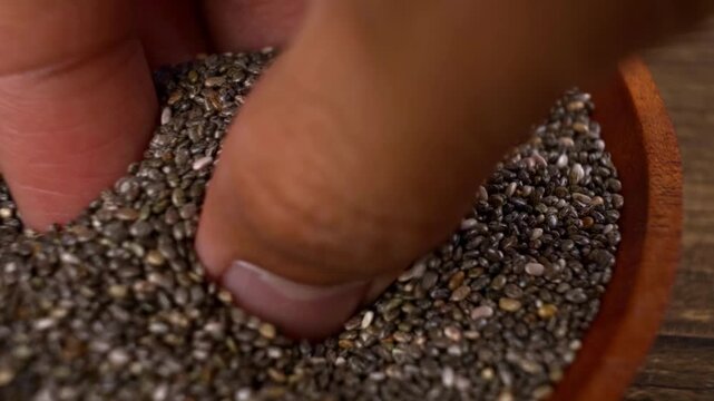 Macro shot of fingers pinching raw chia seeds