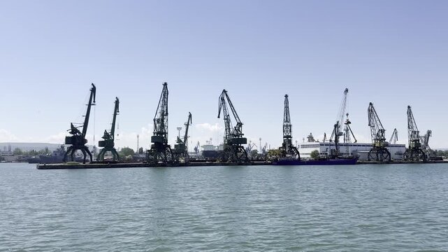 Dock cranes for loading and unloading cargo ships in the port of Varna, Bulgaria. Industrial cranes loading cargo at port with clear blue sky
