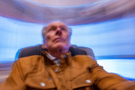 Senior man in desk chair, motion blurred