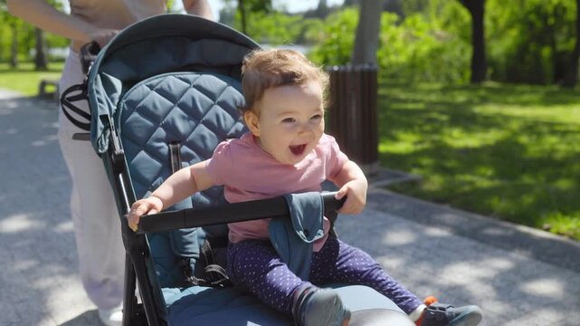 Happy infant baby boy smiling and laughing while riding in a blue stroller.