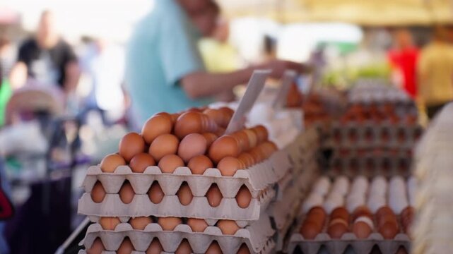 Close-up view of fresh brown eggs stacked in recycled paper cartons on a stand at a busy local farmers market, promoting healthy eating and supporting local agriculture