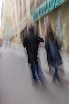 Rear view of couple walking down street, blurred motion
