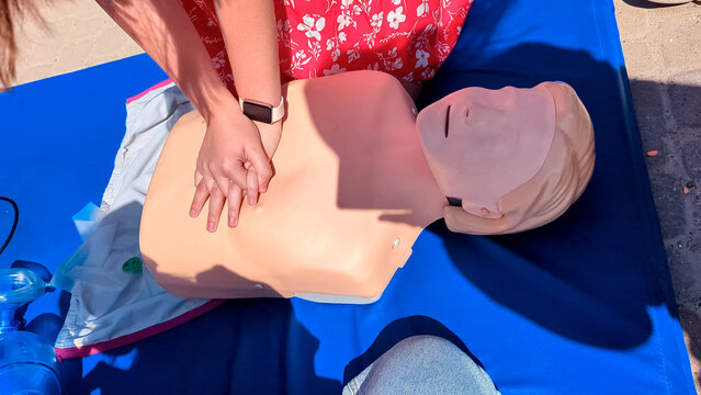  
First aid training with CPR mannequin. Medical students practicing cardiopulmonary resuscitation and using an Ambu bag mask for artificial ventilation during a first aid seminar.