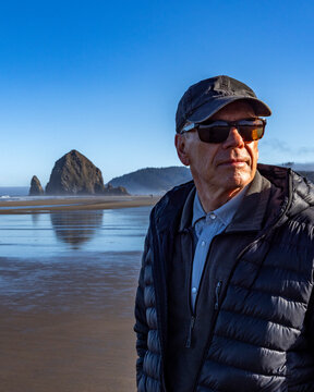 Portrait of senior man on beach with Haystack Rock in background